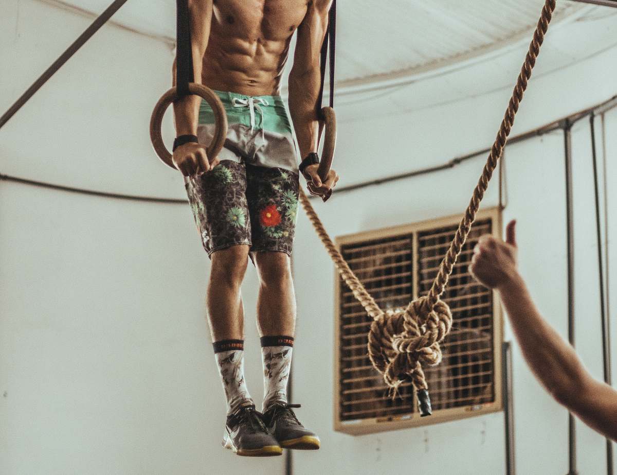 gambaru crossfit man wearing multicolored shorts while exercising on rope inside white room brazil